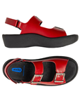 Pair of Red sandals with a closed sides, open back, open toe, adjustable hook-and-loop with buckle accent straps across the top and around the ankle, black Wolky logo'd footbed and thick black platform outsole.