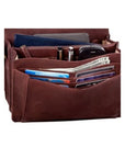 Interior of the 3/4 flap organizer bag in brown, displaying the organizational features. Across the 3 compartments hold credit cards, cash, two pens, a cell phone, a tablet, and another slip pouch.