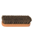 Flat wooden handle with course brown bristles on shine brush