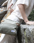 Model wearing olive green Travelon Anti-Theft Heritage Crossbody outdoors, showcasing its stylish and functional travel design.