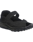 A black Bernie Mev sandal with woven elastic upper, a peep toe and strap across the top of the foot with a closed in heel, and a rocker bottom black outsole.
