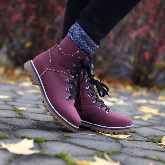 Model posing on a sidewalk wearing the Maika boot in Bordo.