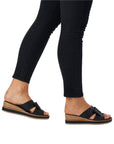 Model wearing black Rieker D6456 slide platform wedges, showcasing casual elegance and lightweight comfort for daily wear.