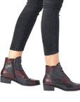 Model wearing burgundy-black Women's Remonte D6882 lace-up boots with black jeans, ideal for stylish fall and winter looks.