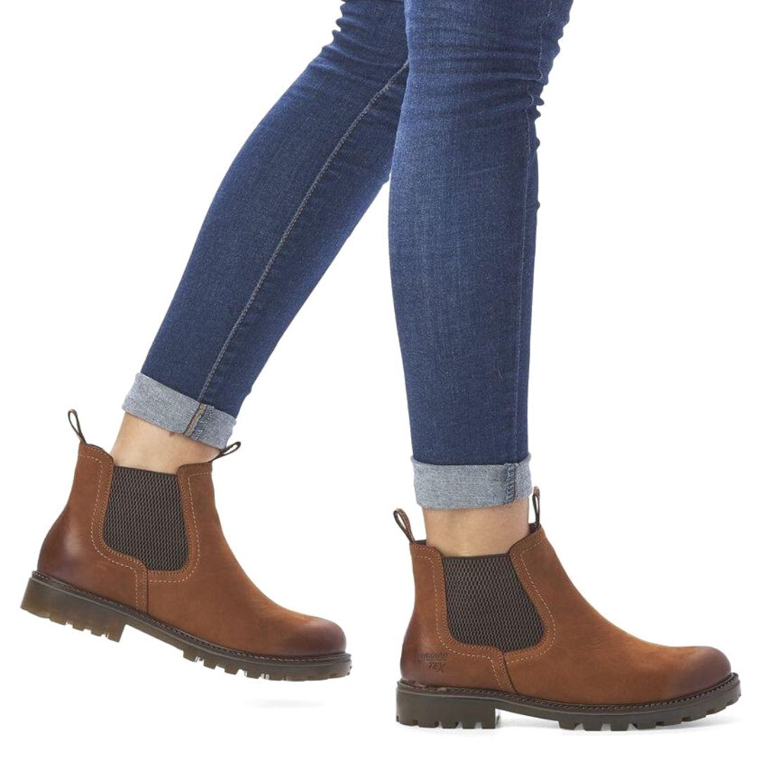 Model wearing brown Women's Remonte D8472 Chelsea Boots with jeans, highlighting ankle height and stylish waterproof leather design.