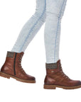 Women wearing jeans and brown mid winter boots with laces and side zipper.