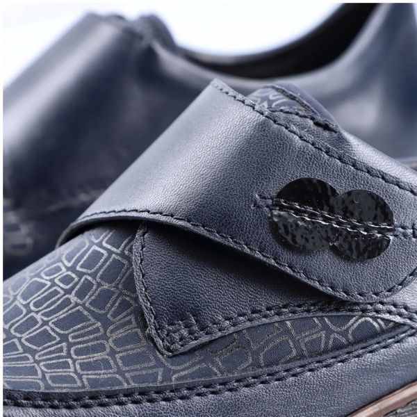 Close-up of navy Rieker 537C0 slip-on shoe showing hook-and-loop strap and embossed pattern for stylish and secure fit.