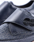 Close-up of navy Rieker 537C0 slip-on shoe showing hook-and-loop strap and embossed pattern for stylish and secure fit.