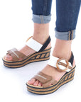 Model wearing tan and white Rieker platform faux cork wedge sandals with rolled jeans.