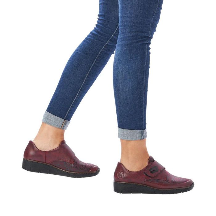 Model wearing red Rieker 537C0 slip-on shoes with jeans, showcasing casual fall style and lightweight wedge comfort.