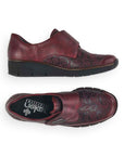 Top and side view of red Rieker 537C0 slip-on shoes for women, featuring floral pattern and flexible sole for casual wear.