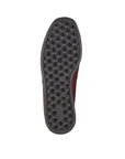 Black treaded outsole of red ankle boot.