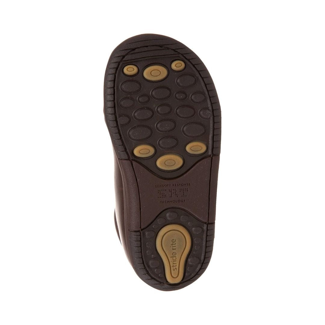 Bottom of brown dress shoes for toddler has pressure point grips in yellow and slip grips in brown