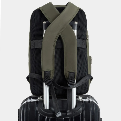 Green backpack with thick shoulder straps sitting on a black suitecase.