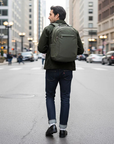 Man walking on a city street wearing a green backpack