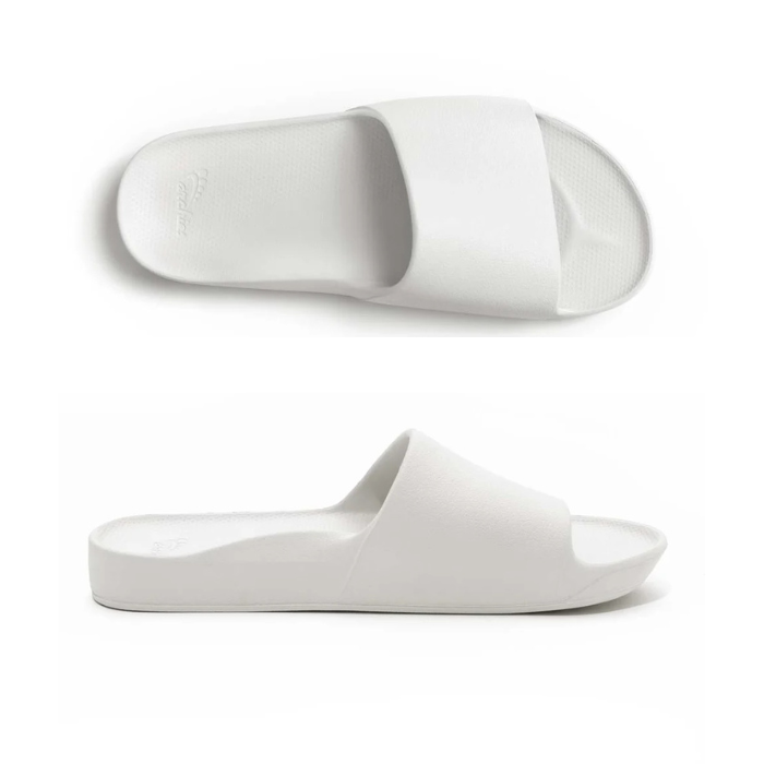 Pair of White slide sandals with Archie logo stamped in heel.