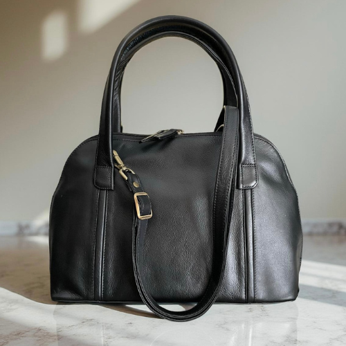 Black leather handbag on a marble surface with a neutral background