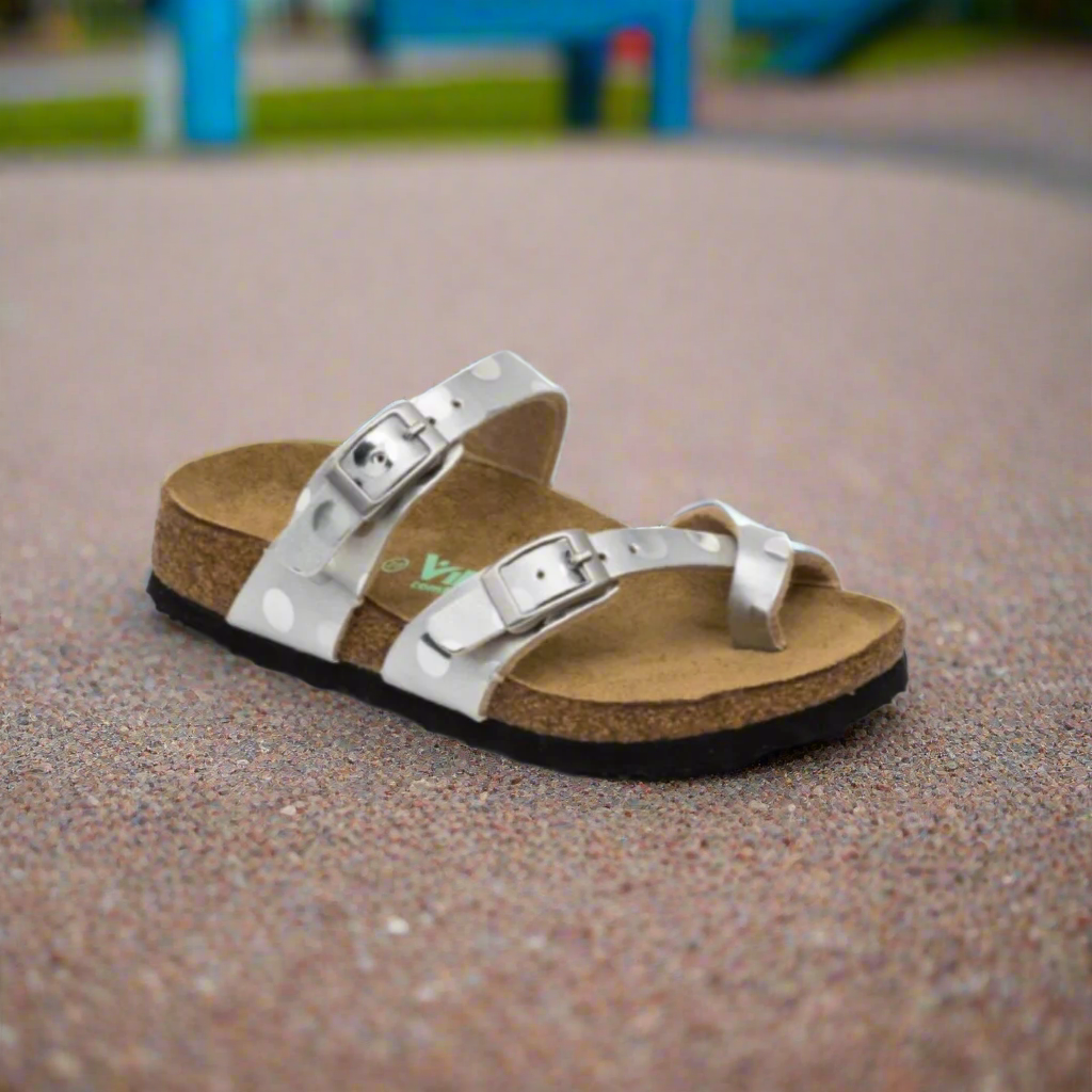 Silver sandal on a textured surface with a blurred playground background