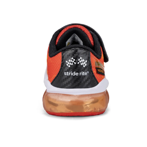 Heel of a Stride Rite sneaker with a vibrant orange and black design with a carbon-fiber pattern heel panel with finishing line race flags and clear orange outsole.