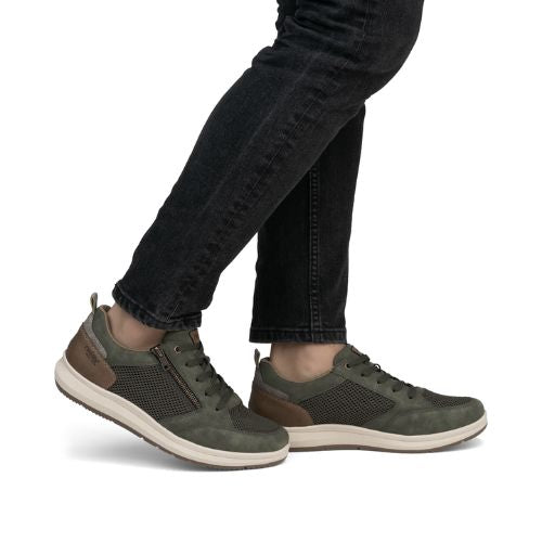 Man in black jeans wearing green casual sneakers.