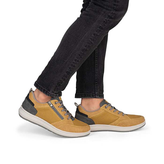 Yellow sneakers with gray accents worn with black jeans.