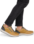 Yellow sneakers with gray accents worn with black jeans.