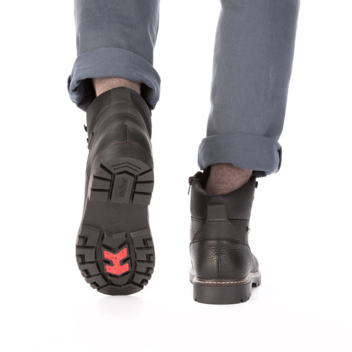 Black leather boots with red outsole grips worn with grey pants.