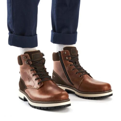 Man in blue rolled up jeans with brown lace-up winter ankle boots on.