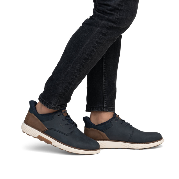 Navy blue shoes with brown accents worn with black jeans.