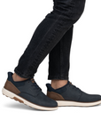 Navy blue shoes with brown accents worn with black jeans.