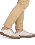 White sneakers with brown accents and outsoles worn with beige pants.