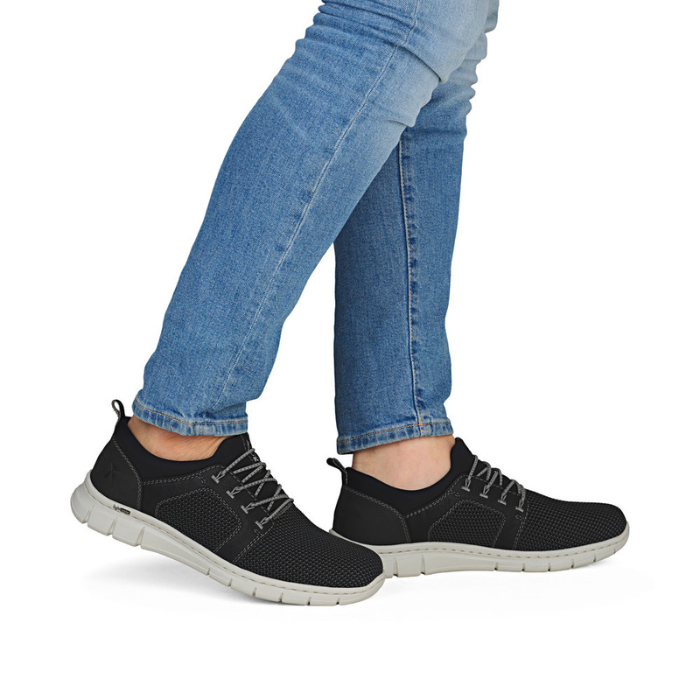 Black slip-on sneakers worn with blue jeans.