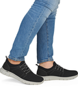 Black slip-on sneakers worn with blue jeans.