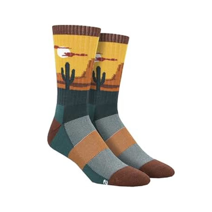 Wool socks with orange, light blue, teal, and navy square pattern on foot, with sunset desert with cactus around ankle and Cuff, heel and toe accents dark rust red color. 
