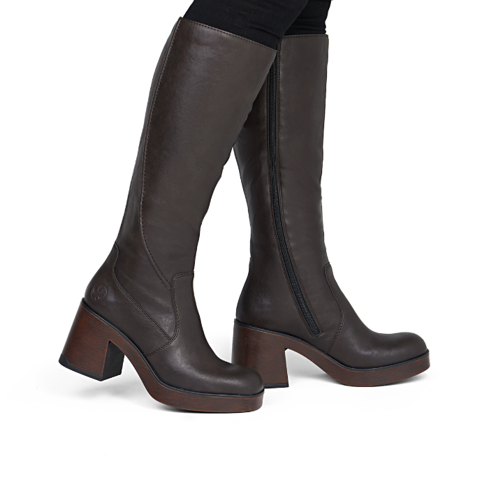 Brown chunky outsole knee high boots worn with black pants.