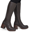 Brown chunky outsole knee high boots worn with black pants.