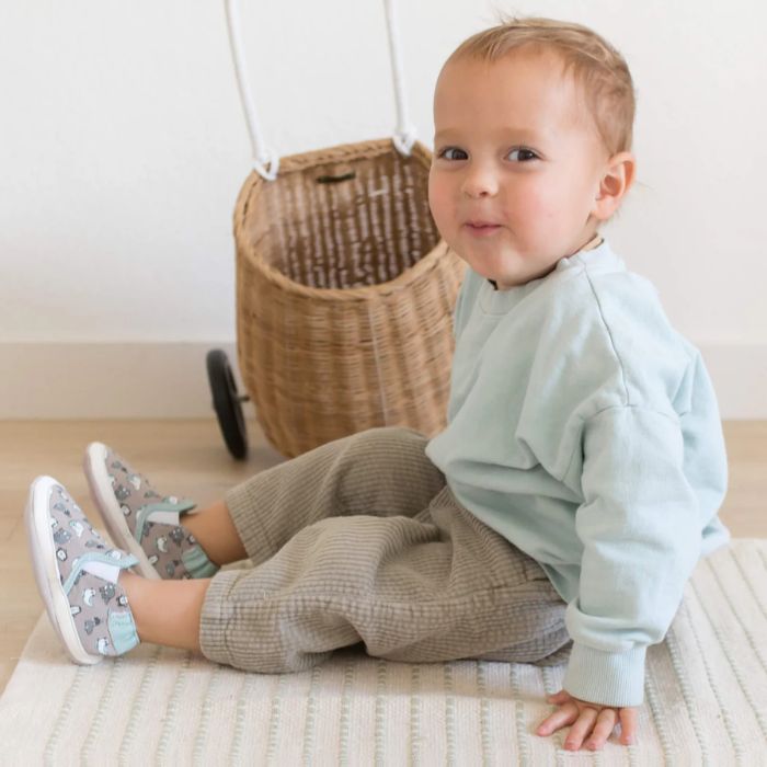Toddler in front of whicker basket wearing Artic Friends soft sole shoes.