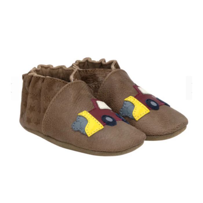 A pair of soft leather baby shoes with construction trucks on each foot.