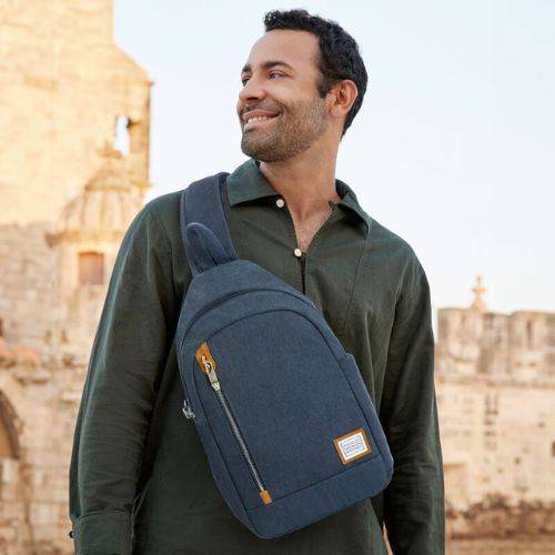 Man carrying Travelon Anti-Theft Sling Bag across chest, highlighting its ergonomic fit, anti-theft features, and modern travel-ready style.