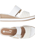 Pair of White wedge slide sandals with a white buckle strap, gold accents, woven over-the-toe Velcro strap, tan Remonte logo'd footbed, white midsole and tan outsole.