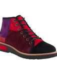 A high-top patchwork ankle boot featuring suede panels in red, burgundy, purple, and black, with black laces and a black outsole.