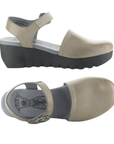 Pair of Taupe closed toe sandals with backstrap, grey Fly London logo'd footbed and a lugged black wedge platform.
