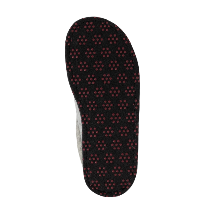 Outsole of a black slipper with repeating pattern of small red circular dots (traction dots).

