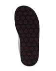 Outsole of a black slipper with repeating pattern of small red circular dots (traction dots).
