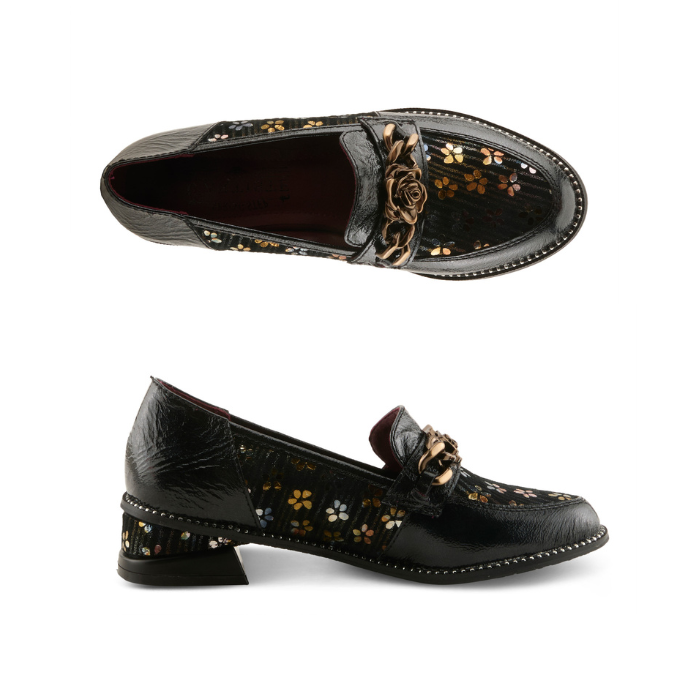 Pair of glossy black leather loafers with dark yellow and blue floral pattern on the side panels, a decorative burnished gold metal rose on chain embellishment on the vamp, and black sculptured low block heel.