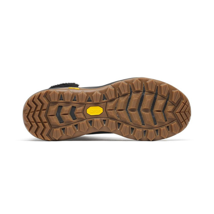The outsole of a brown rugged boot, showing deep tread patterns and a small yellow Vibram logo in the center.