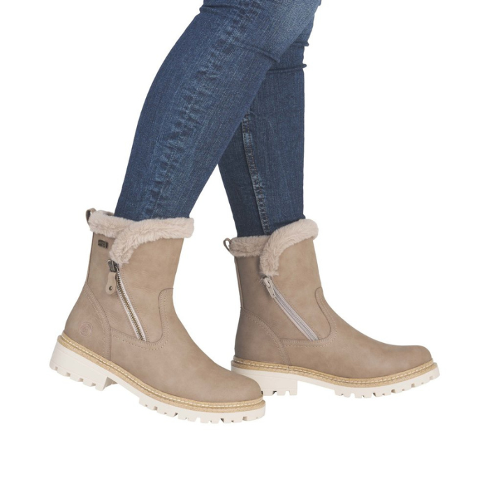 Beige winter boots with fur trim worn with blue jeans.