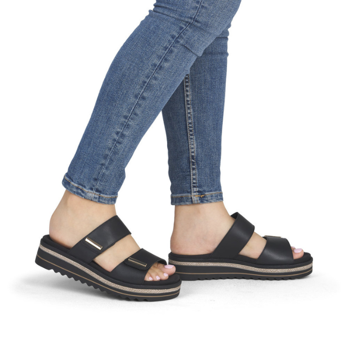 Black slide sandals worn with blue jeans.