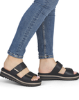 Black slide sandals worn with blue jeans.