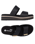 Pair of Black slide sandals with two Velcro straps, gold bar accents on each strap, black Remonte logo'd footbed, and a black platform with brown accents.